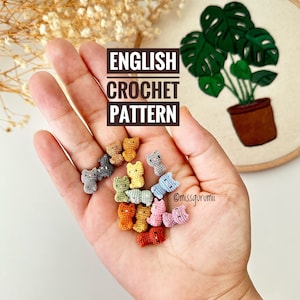 Könnte beinhalten: Eine Sammlung von 15 bunten gehäkelten Katzen-Amigurumi-Spielzeugen in verschiedenen Blautönen, Grüntönen, Gelbtönen, Orangetönen, Rosatönen und Brauntönen. Die Spielzeuge sind in einer Hand angeordnet, im Hintergrund ist der Text "ENGLISH CROCHET PATTERN" und "@missgurumii" zu sehen.