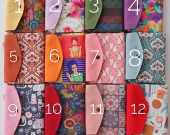 May include: Twelve colorful fabric pouches with different patterns and designs. Each pouch has a number from 1 to 12 printed on the front. The pouches are arranged in four rows of three.