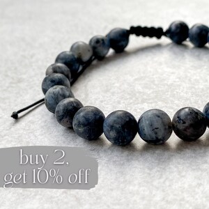 May include: A black beaded bracelet with dark blue gemstones. The bracelet has a simple knot closure. The text "buy 2, get 10% off" is visible in the image.