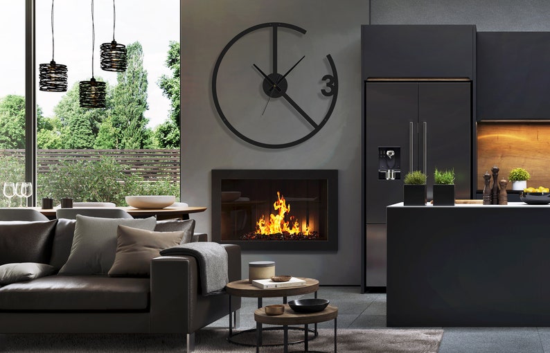 May include: A modern living room with a black fireplace, a black leather sofa, and a large black clock on the wall. The clock has a unique design with a circle and a line through it. The room is decorated in a minimalist style with a gray rug and two round coffee tables.