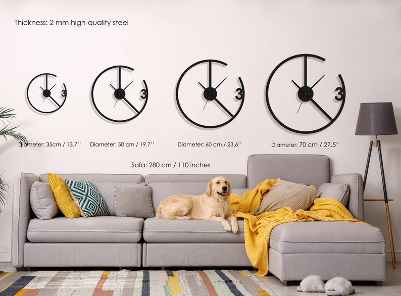 May include: Four black metal wall clocks with different diameters, ranging from 13.7 inches to 27.5 inches. The clocks are hanging on a white wall above a gray sofa with yellow throw blankets. The text "Thickness: 2 mm high-quality steel" is visible at the top of the image.