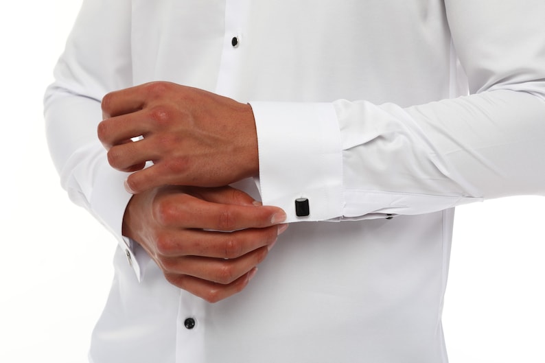 May include: A white dress shirt with black cufflinks. The shirt has a button-down collar and long sleeves.