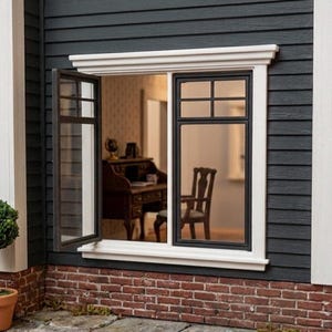 Puede incluir: Una ventana de casa de muñecas en miniatura con marco blanco en un revestimiento horizontal gris oscuro sobre una base de ladrillo. La ventana tiene un marco negro con una hoja que abre a la izquierda, mostrando un escritorio y silla.