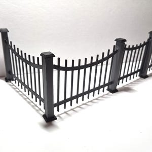 May include: A black miniature fence with a curved design. The fence has vertical bars and is made of a dark material. The fence is a decorative item, possibly for a model or diorama.
