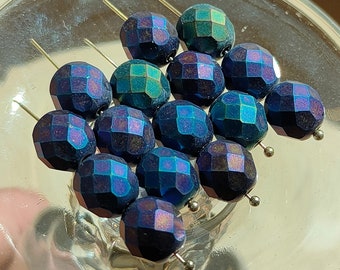 May include: A collection of 14 iridescent blue and green faceted glass beads with silver pins.