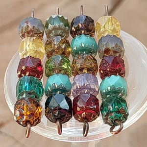 May include: Four vertical strands of multi-colored, faceted glass beads arranged in a grid. The beads feature various hues including yellow, green, red, blue, purple, and brown, each with a reflective, cut surface and a small metal loop at the base.