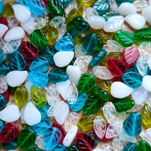 May include: Assortment of glass leaf-shaped beads in various colors, including clear, blue, green, red, and white. The beads are perfect for jewelry making, crafting, and home decor.