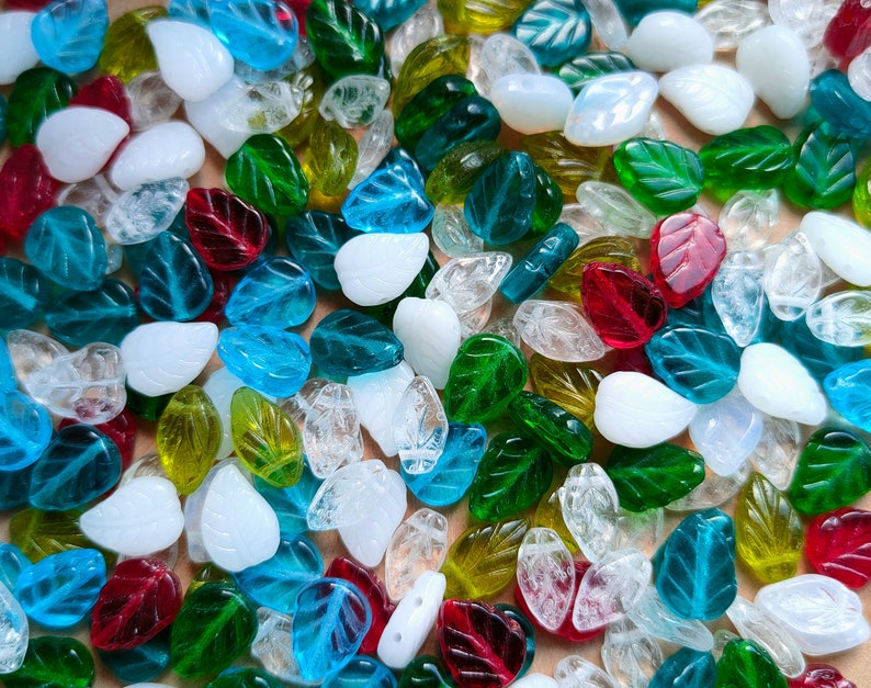 May include: Assortment of glass leaf-shaped beads in various colors, including clear, blue, green, red, and white. The beads are perfect for jewelry making, crafting, and home decor.