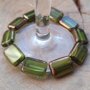 May include: A close-up of a glass stemware base decorated with a ring of green iridescent glass beads.
