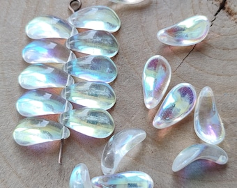 May include: A collection of clear, iridescent teardrop-shaped beads. The beads have a pearlescent sheen, reflecting a rainbow of colors. Some beads are strung together, while others are loose. Ideal for jewelry making or craft projects.
