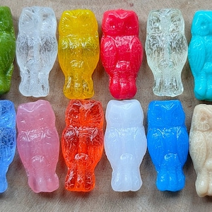 May include: Twelve small owl-shaped glass figurines in various colors, including green, clear, yellow, red, blue, pink, orange, and beige.
