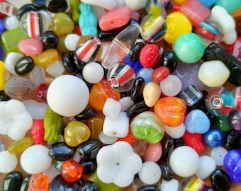 May include: A large assortment of colorful glass beads in various shapes and sizes. The beads include clear, white, red, blue, green, yellow, orange, and black. Some beads have stripes or patterns.
