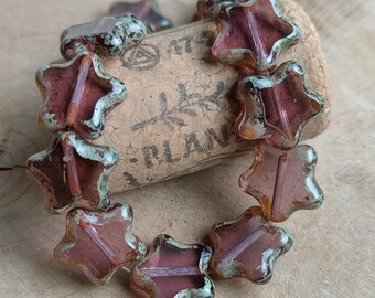 May include: A strand of star-shaped glass beads with a mottled, iridescent finish in shades of purple and green. The beads are arranged in a circle around a cork.