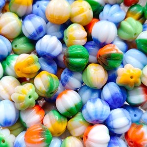 Puede incluir: Una colección de cuentas de vidrio de colores en varias formas y tamaños. Las cuentas son principalmente blancas, azules, verdes y amarillas con algunos acentos rojos y naranjas. Las cuentas son perfectas para hacer joyas o manualidades.