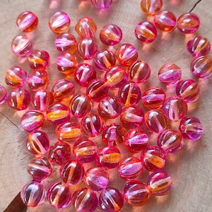 以下が含まれることがあります： ピンクとオレンジのガラスビーズがたくさんあります。ビーズは丸く、滑らかで光沢のある仕上がりです。