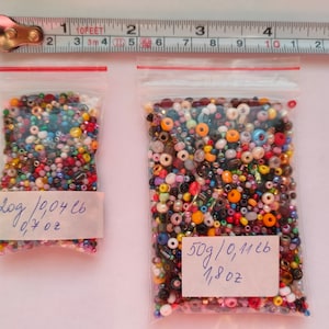May include: Two bags of colorful seed beads. The smaller bag contains 209 beads weighing 0.7 ounces and the larger bag contains 50 grams of beads, which is 0.1126 pounds or 1.8 ounces.