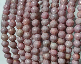 May include: A strand of pink and white glass beads with a faceted, irregular shape. The beads have a mottled, marbled appearance.