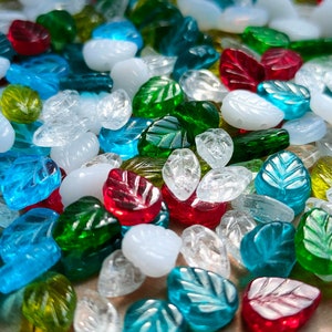 May include: Assortment of glass leaf-shaped beads in various colors, including clear, green, blue, and red. The beads are perfect for jewelry making or crafting projects.