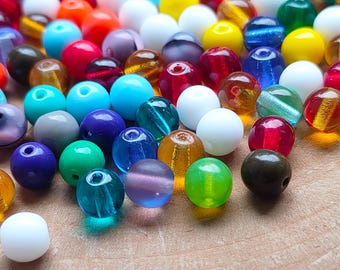 May include: A collection of colorful glass beads in various sizes and shades. The beads are a mix of opaque and translucent, with colors including red, blue, green, yellow, and white. These beads are perfect for jewelry making and crafting.