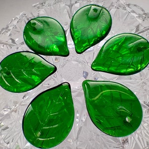 Könnte beinhalten: Sechs grüne, glasartige Blätter mit strukturierter Oberfläche. Die Blätter sind in Form einer Blume angeordnet.