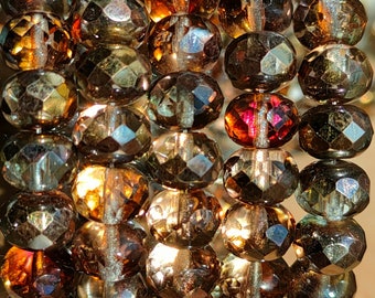 May include: A strand of iridescent brown glass beads with faceted surfaces. The beads are strung together on a clear thread and have a shimmering, reflective quality.