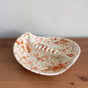 May include: A white ceramic mug with a black handle and the text "But First, Coffee" in a bold, black font. The mug is set against a blurred background, suggesting a cosy setting.