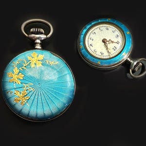 May include: Two round pocket watches with bright turquoise guilloch&eacute; enamel cases. One watch shows a gold floral overlay on the back, while the other displays a white dial with black Arabic numerals and gold hands, featuring a turquoise enamel bezel.