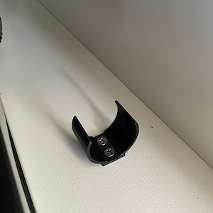 Puede incluir: Soporte de estante de plástico negro con dos tornillos.