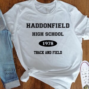 Könnte beinhalten: Weißes T-Shirt mit schwarzem Text, der "Haddonfield High School 1978 Track and Field" lautet.