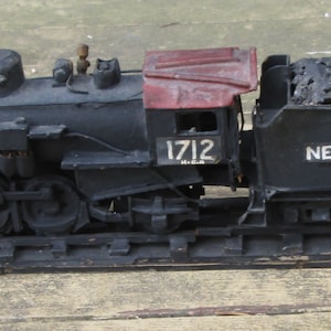 May include: A black toy train with a red caboose and a coal car. The train is labeled "New York Central" and has the number "1712" on the side.