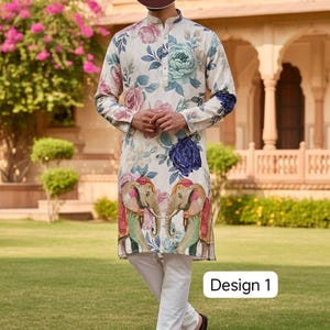 May include: A cream-colored kurta with a floral pattern in pink, blue, and green, paired with white pants. The kurta features a design of two elephants and the text "Design 1". The outfit is worn with brown shoes.