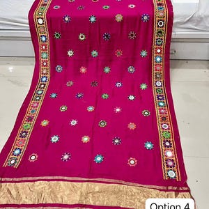 May include: A magenta textile with intricate embroidery and mirror work. The edges are adorned with colorful geometric patterns and small mirrors. The textile features numerous small, circular mirrors and the text "Option 4".