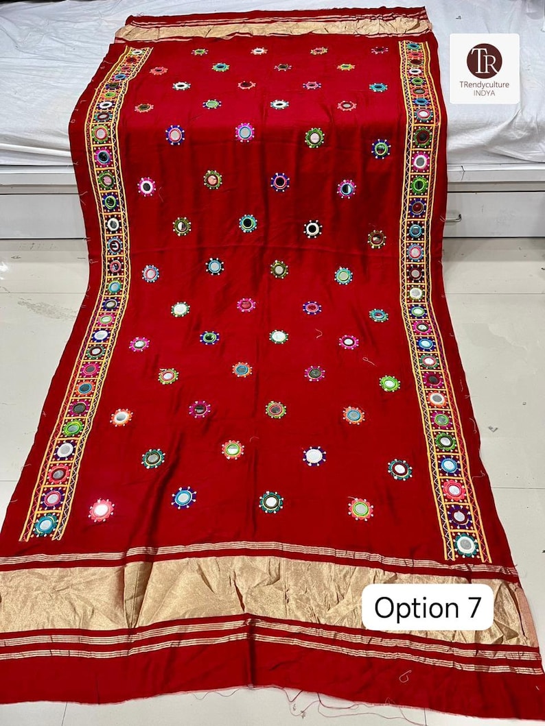 May include: A vibrant red textile with intricate embroidery and mirror embellishments. The fabric features a repeating pattern of colorful circular designs and a decorative border. The text "Option 7" is visible in the lower right corner.