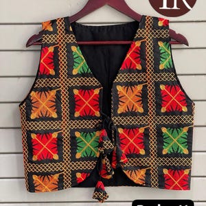 May include: Black vest with a V-neck and colorful embroidered geometric patterns in red, orange, and green. The vest has a tie closure and tassels. The text "Design 11" is in a black box at the bottom.