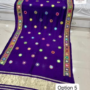 May include: A vibrant purple textile with intricate embroidery and mirror work. The edges feature a detailed border with colorful geometric patterns. Scattered across the fabric are small, circular mirrors, adding a reflective quality. The bottom edge has a gold metallic trim. The text "Option 5" is visible.