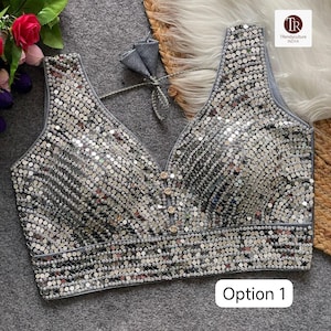 Peut inclure: Haut argenté à paillettes avec un décolleté en V et de petits boutons dorés au centre. Le haut est sans manches et possède une bordure grise. Le texte "Option 1" est visible dans un encadré blanc en bas.