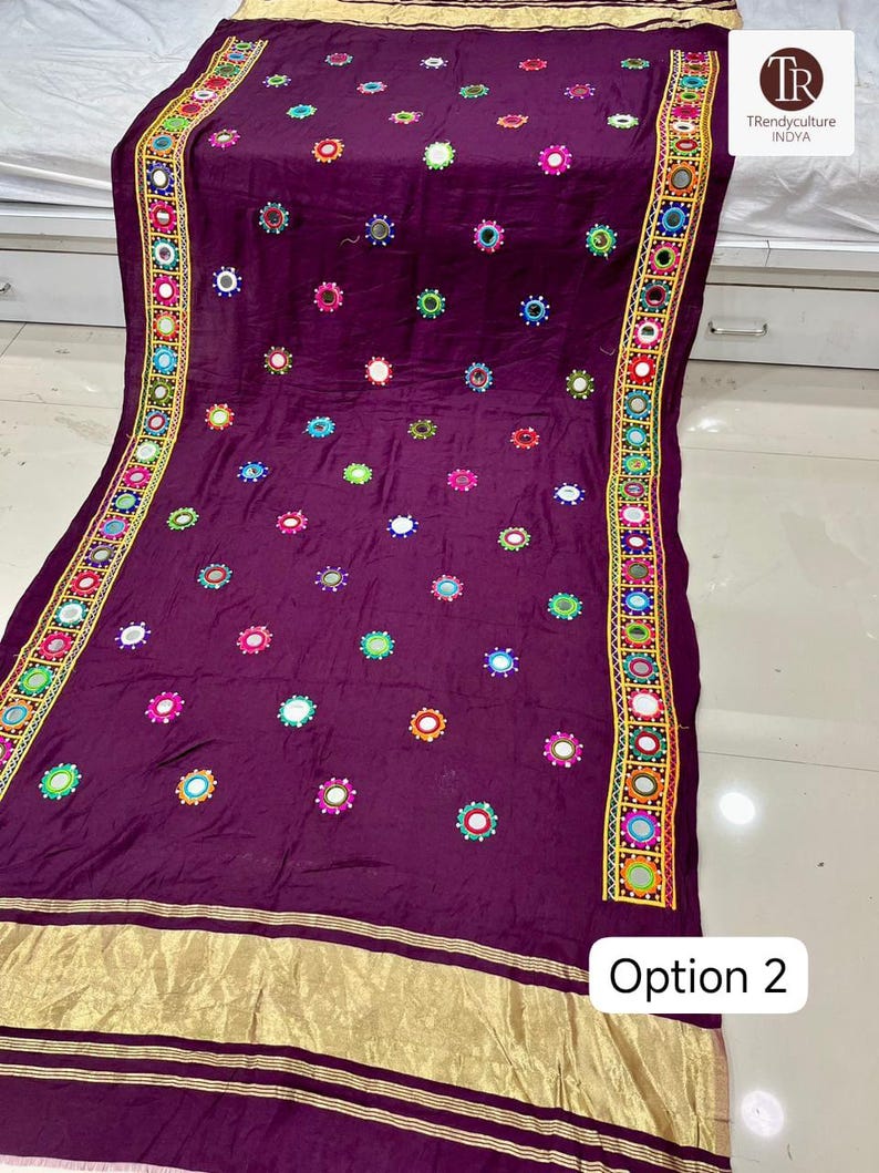 May include: A deep purple textile with colorful embroidered mirror accents. The fabric features a gold border and trim with the text "Option 2". The design includes a repeating pattern of small mirrors and embroidered details.