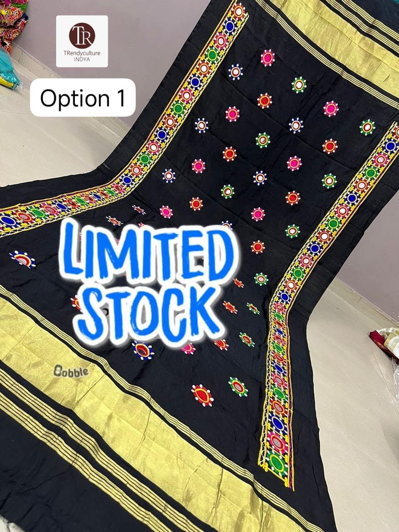 May include: Black textile with colorful embroidered floral patterns and gold trim. The textile has the words "LIMITED STOCK" in a blue font. The textile is from Trendyculture Indya.