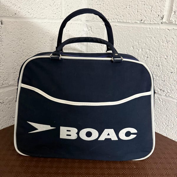 Bolso de vuelo Boac de los años 60. Acabado en azul marino con logotipo y ribete en blanco. Excelente estado, prácticamente sin uso.