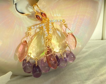 Puede incluir: Pendientes de aro dorados con una barra de cristal y múltiples piedras preciosas en forma de lágrima en tonos de morado, rosa y amarillo.
