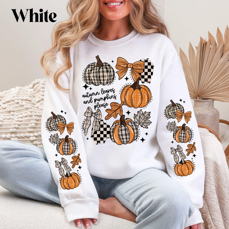 May include: White sweatshirt with an autumn-themed design. The design includes pumpkins, bows, and leaves in orange, brown, and black plaid patterns. The text "autumn leaves and pumpkins please" is also featured.