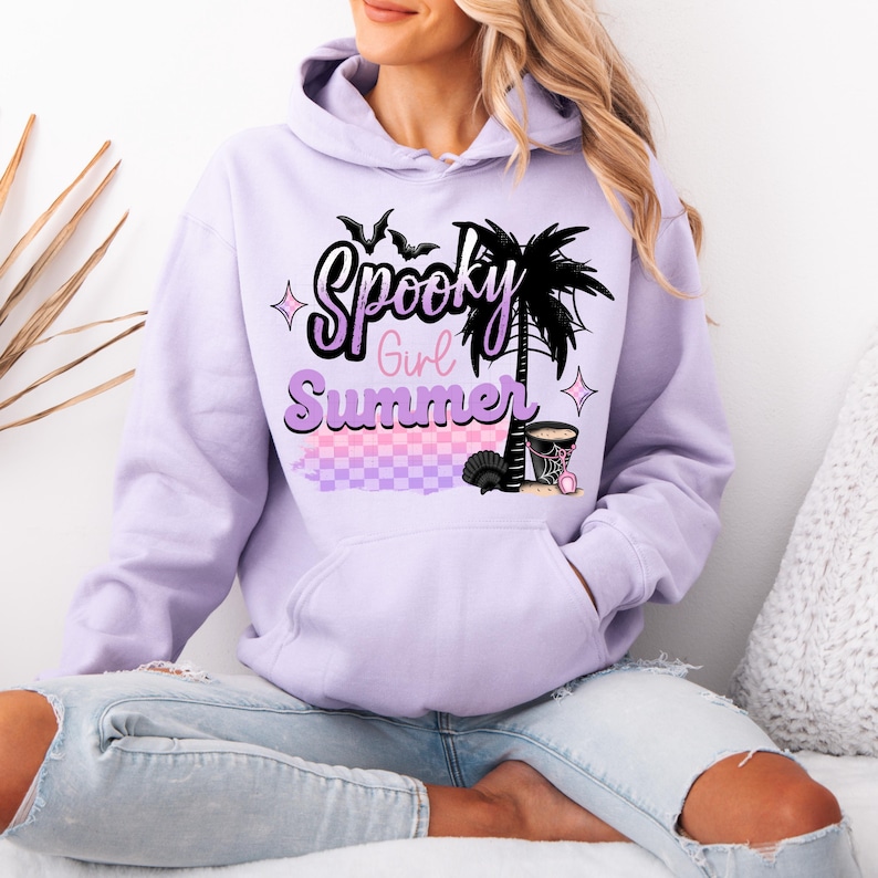 Pu&ograve; includere: Una felpa con cappuccio color lavanda con una stampa grafica di una palma, pipistrelli e il testo "Spooky Girl Summer".