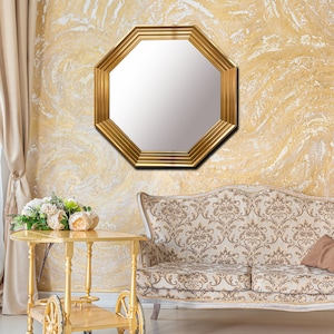 May include: A gold octagonal mirror with a beveled edge hangs on a yellow and white marbled wall above a white and brown patterned sofa.