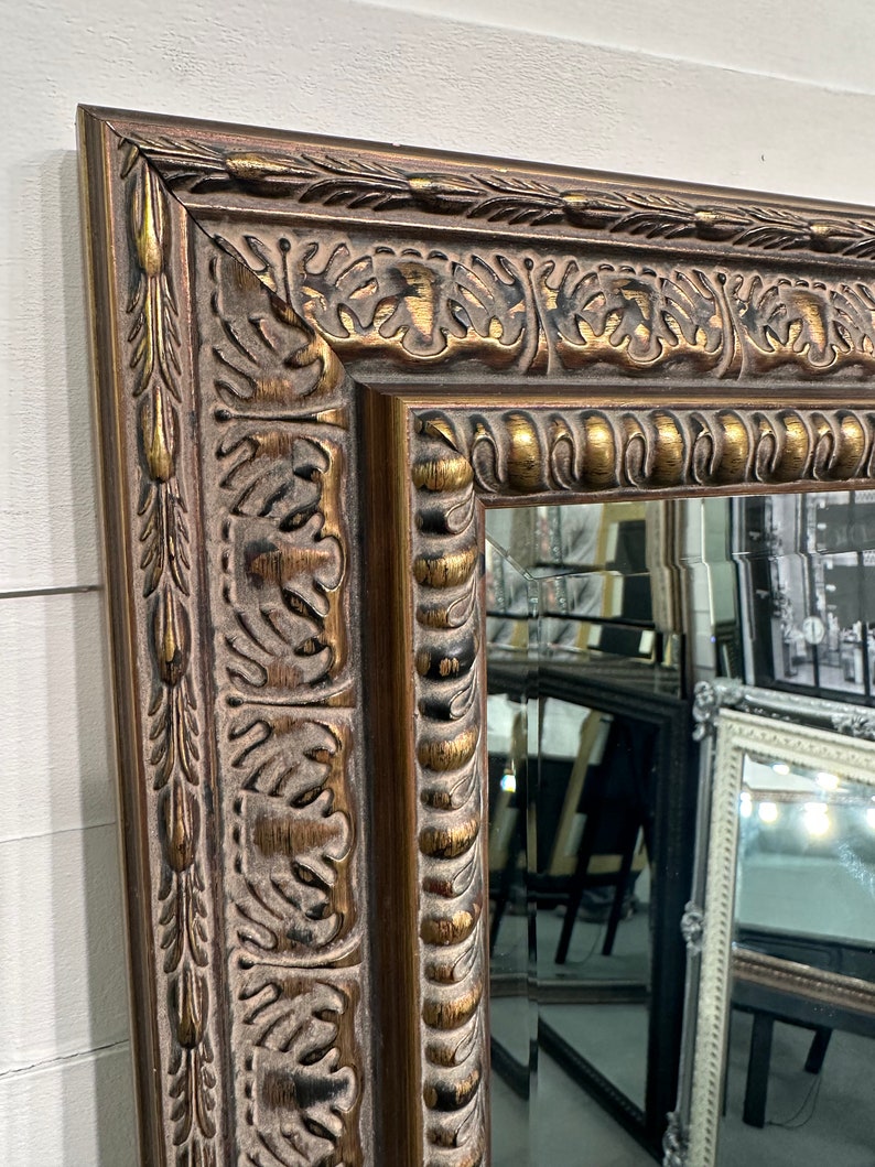 May include: A large, ornate mirror with a gold-toned frame. The frame has a detailed, carved design with a distressed finish.