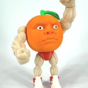 Può includere: Una statuetta originale di un'arancia con un volto umano, braccia e gambe muscolose, che indossa slip rossi e scarpe da ginnastica bianche con dettagli rossi. L'arancia ha una foglia verde e sta flettendo il braccio.