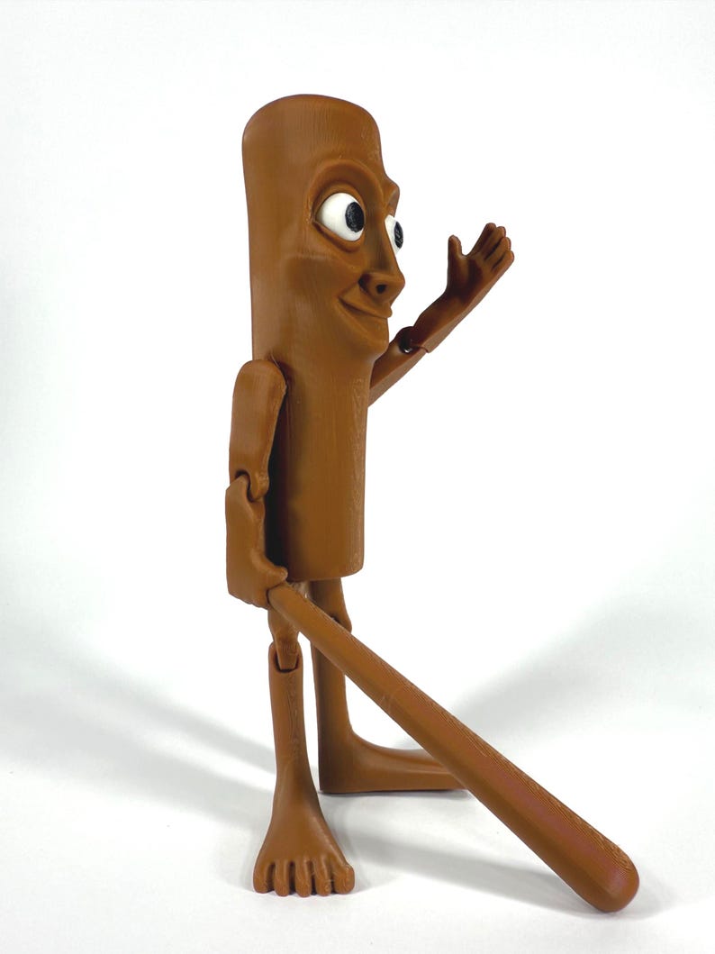 May include: A brown, articulated figurine with a cylindrical body, a smiling face, and outstretched arm. The figure has a long, brown appendage extending from its lower body. The figure is standing on a white surface.