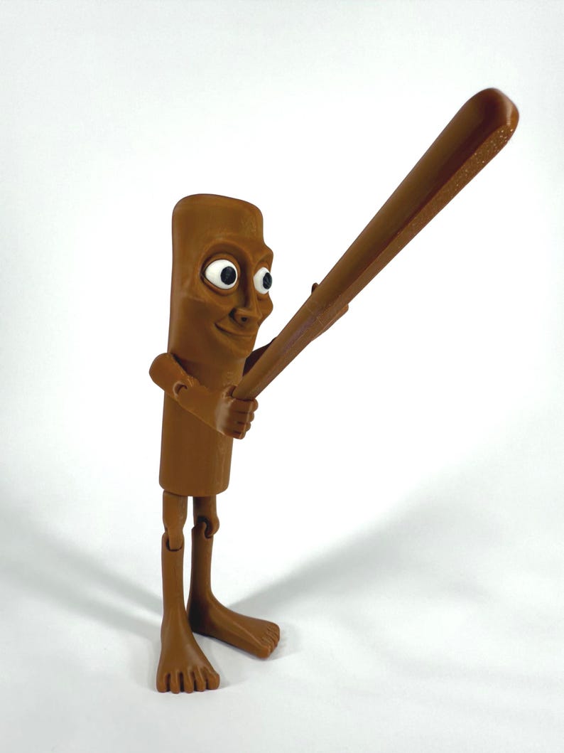 May include: A brown, articulated figurine of a cartoon character holding a baseball bat. The figure has a rectangular body, a smiling face with large eyes, and bare feet. The bat is also brown.