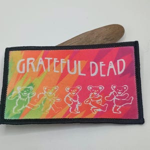 May include: A colorful patch with the words "Grateful Dead" in white text. The patch features five dancing bears in a tie-dye pattern.