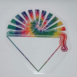 May include: A clear, geometric sticker featuring a tie-dye cat silhouette with a rainbow sunburst design. The cat is lying down, and the sticker has a white, blank triangle at the bottom. The sticker is a vibrant, colorful design.