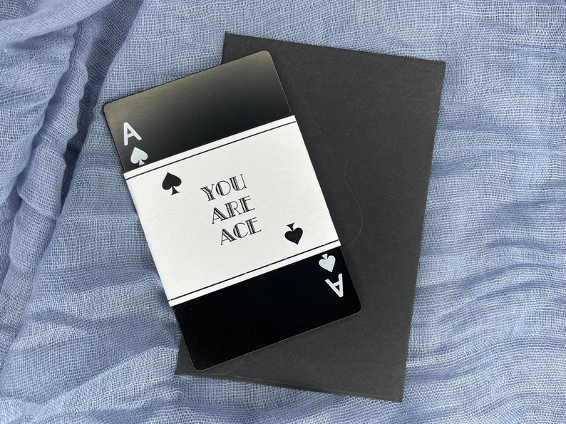 Może przedstawiać: Czarna karta z białym obramowaniem i tekstem "You are Ace" w środku. Karta ma symbol pika w lewym g&oacute;rnym rogu i literę "A" w prawym dolnym rogu.